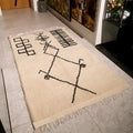 Beige rug with black abstract designs on a tiled floor